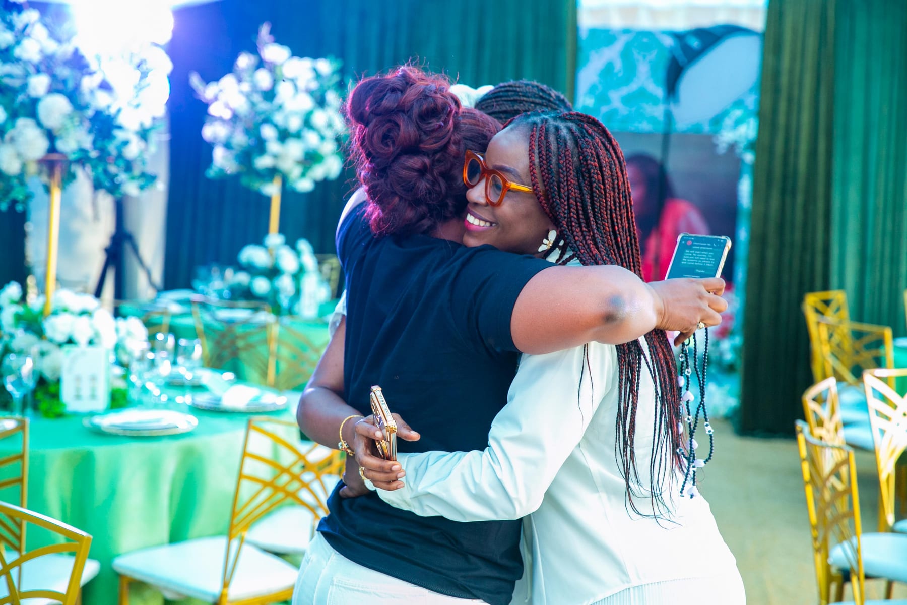 Two guests embracing beside a set table at Kaine Diete-Spiff’s fiftieth birthday